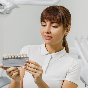 A lady holding dental veneers in hand