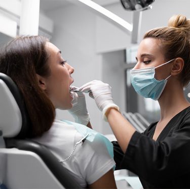 La Dra. Paola Argaez, dentista de habla hispana en Pearland, examina a un paciente en Pearly Whites of Pearland.