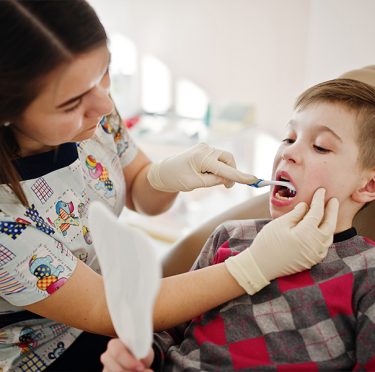 La Dra. Paola Argaez, dentista de habla hispana en Pearland, TX, examina a un paciente joven.