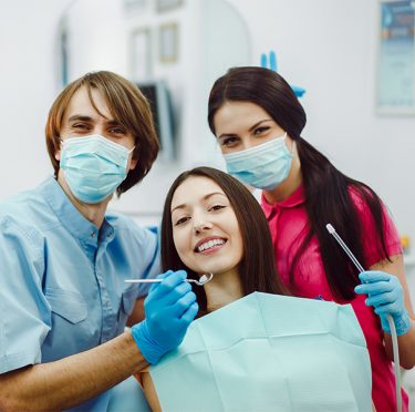 El equipo dental de Pearly Whites of Pearland con un paciente, mostrando un ambiente amigable y profesional.