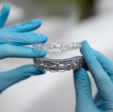 Dentista sosteniendo alineadores transparentes en Pearly Whites de Pearland.