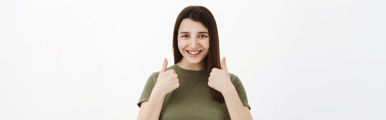 Mujer sonriente dando pulgares hacia arriba en Pearly Whites of Pearland, dentista en Pearland TX.